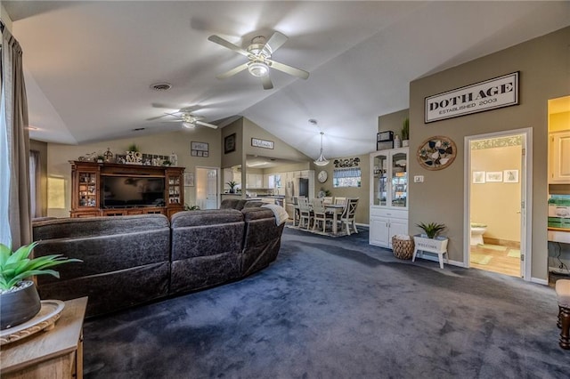 carpeted living room with visible vents, lofted ceiling, baseboards, and ceiling fan