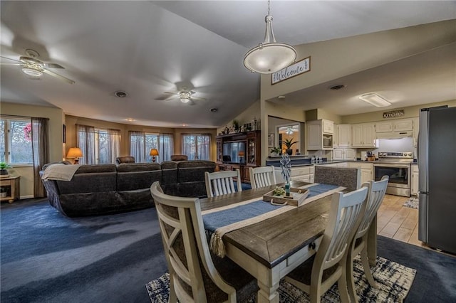 dining room featuring carpet flooring, a ceiling fan, and vaulted ceiling