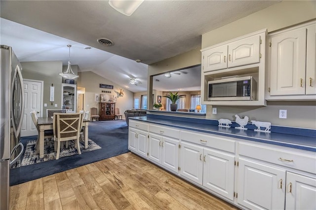 kitchen with dark countertops, visible vents, lofted ceiling, stainless steel appliances, and white cabinetry