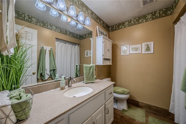 full bathroom with visible vents, baseboards, toilet, wood finished floors, and vanity