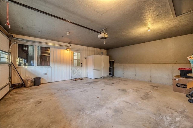 garage featuring a garage door opener and freestanding refrigerator