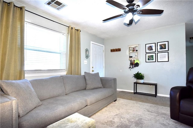 carpeted living area with visible vents, baseboards, and a ceiling fan