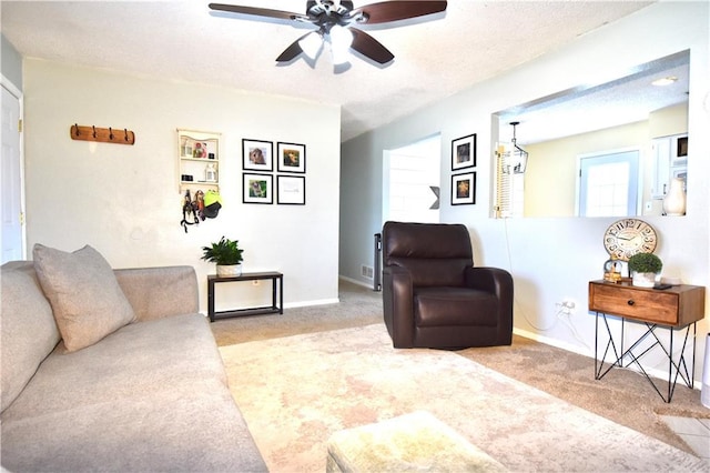 living area featuring baseboards, carpet flooring, a textured ceiling, and a ceiling fan