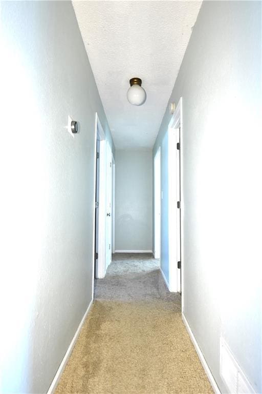 corridor with carpet flooring, baseboards, and a textured ceiling