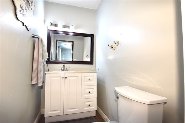 half bath with baseboards, toilet, and vanity