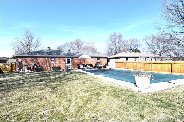 rear view of house with brick siding, a fenced backyard, a lawn, and a patio area