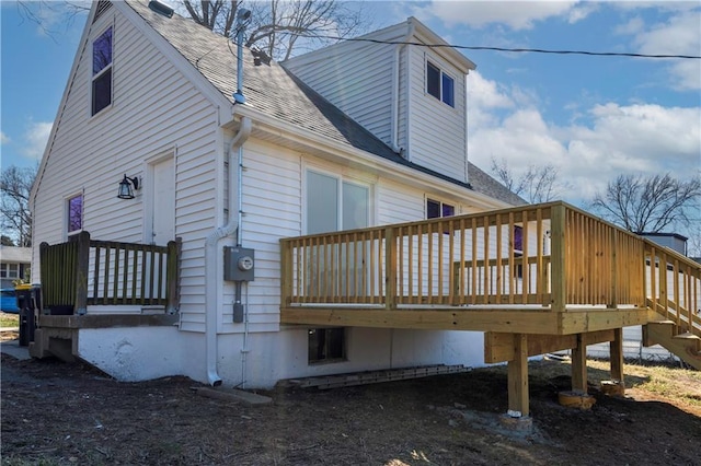 view of property exterior with a deck and a shingled roof