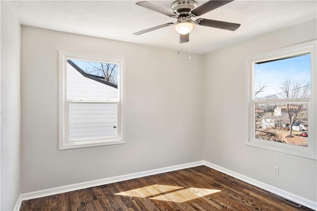 empty room featuring a wealth of natural light, baseboards, a ceiling fan, and dark wood-style flooring