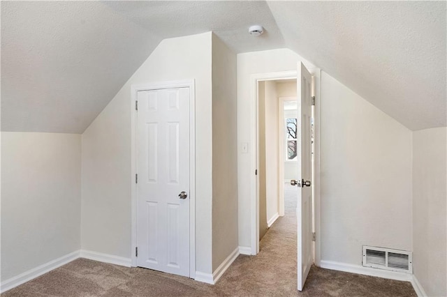 bonus room featuring baseboards, visible vents, lofted ceiling, a textured ceiling, and carpet flooring