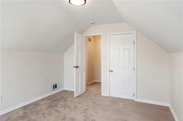 additional living space with light colored carpet, vaulted ceiling, baseboards, and visible vents