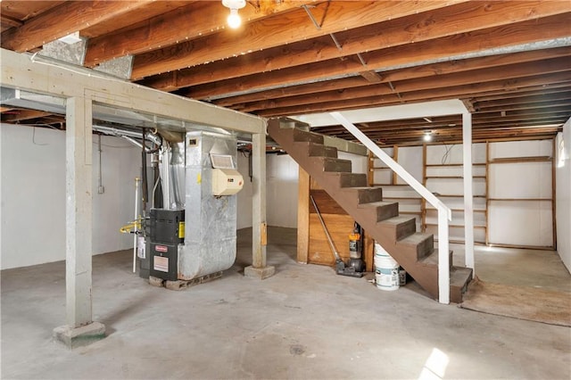 unfinished basement featuring stairs and heating unit