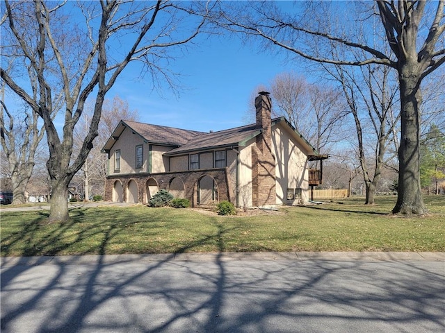 view of side of property with stucco siding, a chimney, and a yard