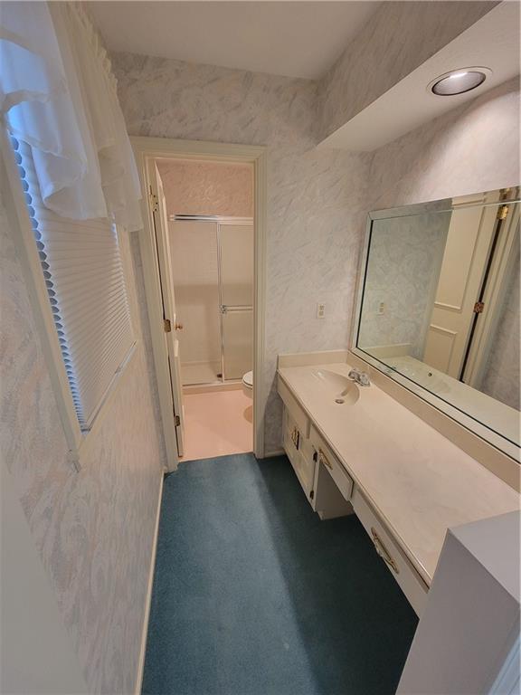 full bath with vanity, toilet, and a shower with door