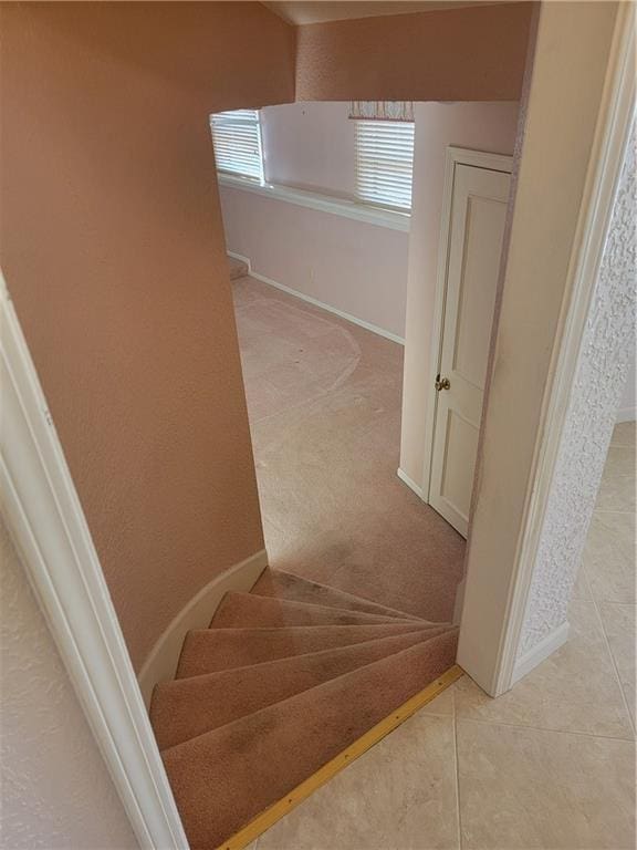 staircase featuring tile patterned floors, baseboards, and carpet