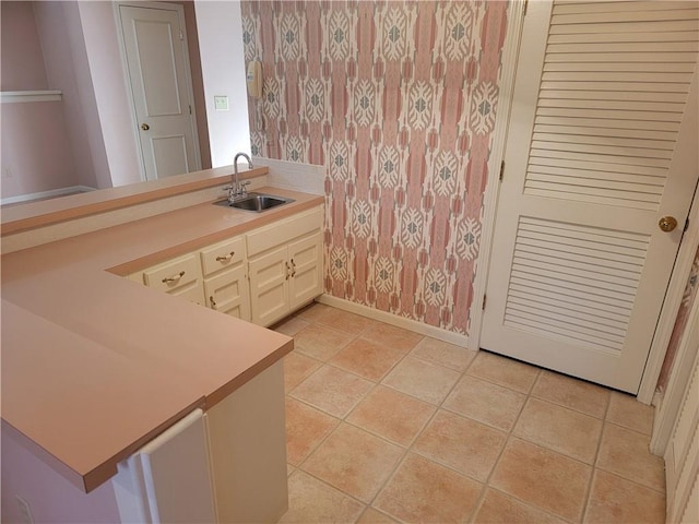 bathroom featuring a sink, baseboards, tile patterned floors, and wallpapered walls