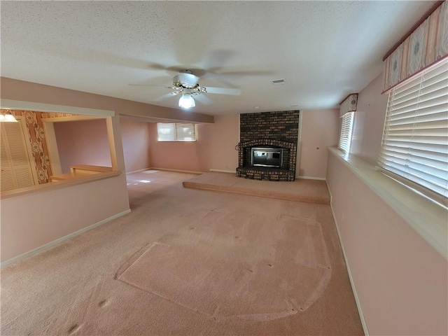 unfurnished living room featuring baseboards, carpet floors, a textured ceiling, and a brick fireplace