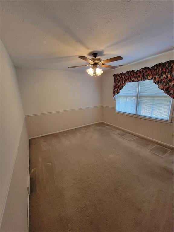 carpeted spare room with a ceiling fan and a textured ceiling