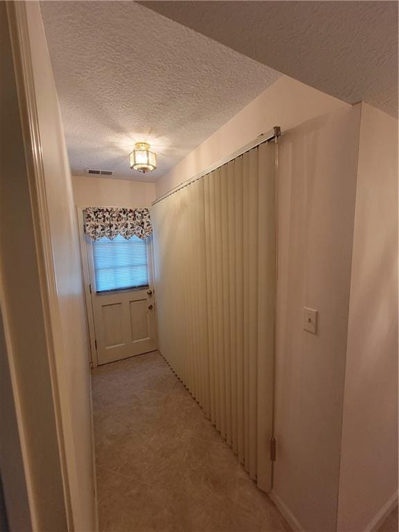 hallway featuring visible vents and a textured ceiling