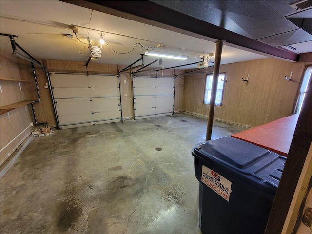 garage featuring visible vents, wooden walls, and a garage door opener