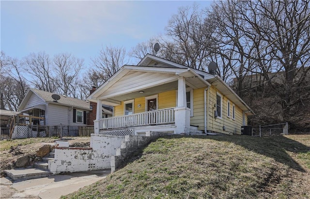 view of front of home featuring a front yard, cooling unit, fence, and covered porch