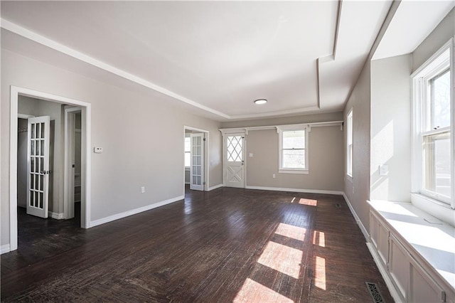 spare room featuring visible vents, dark wood-type flooring, and baseboards