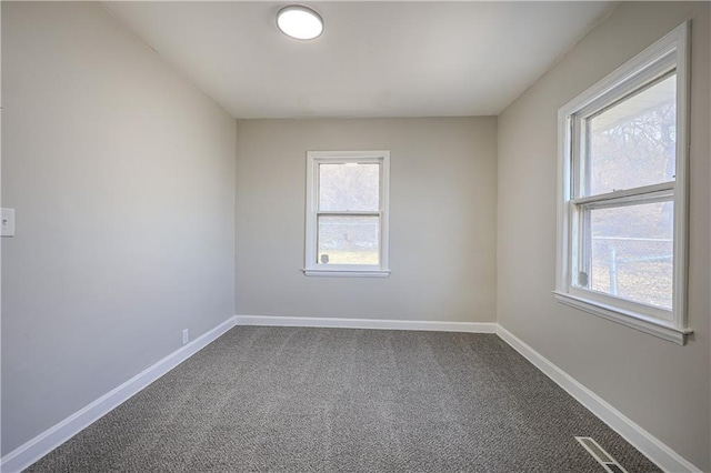 carpeted spare room featuring visible vents and baseboards