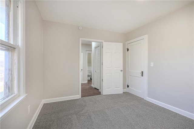 unfurnished bedroom featuring carpet flooring, multiple windows, and baseboards