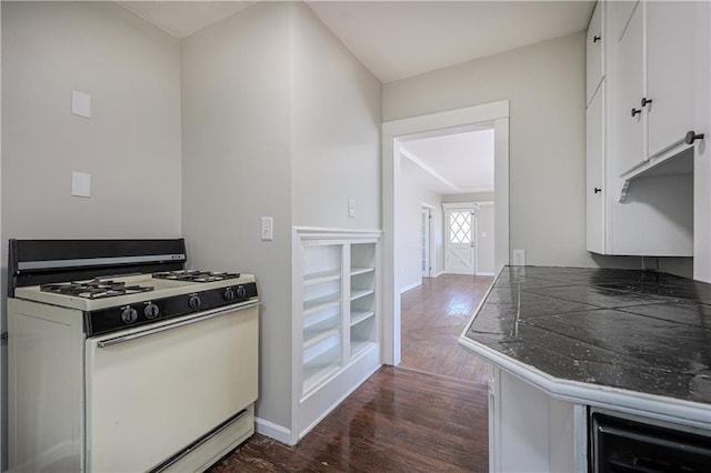 kitchen with baseboards, gas range gas stove, white cabinets, and dark wood finished floors