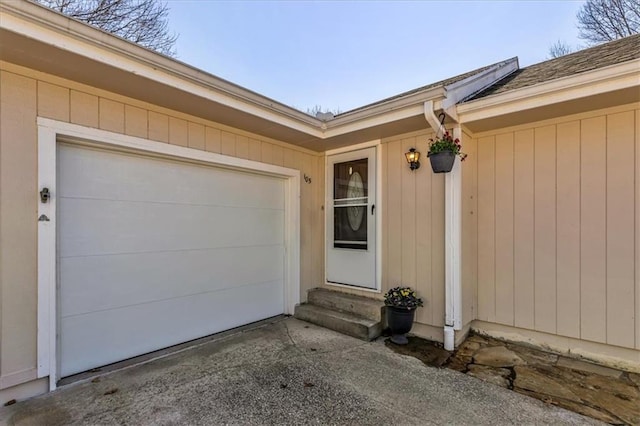 view of exterior entry featuring an attached garage and driveway