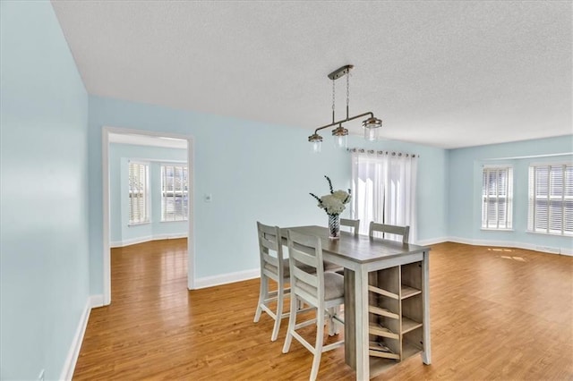dining space featuring wood finished floors, baseboards, and a textured ceiling