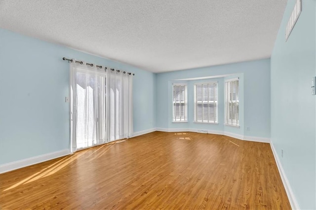 empty room with wood finished floors, baseboards, and a textured ceiling