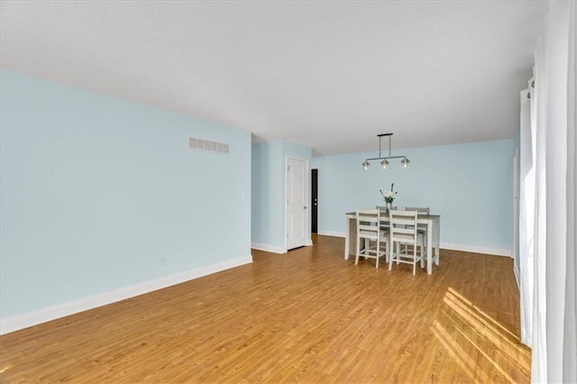 unfurnished dining area featuring light wood-style flooring, baseboards, and visible vents