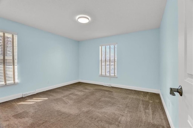 carpeted empty room with visible vents, baseboards, and a wealth of natural light