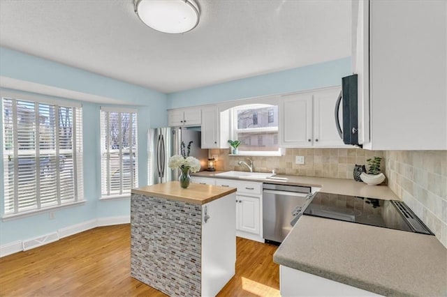 kitchen featuring a sink, stainless steel appliances, light wood-style floors, and white cabinetry