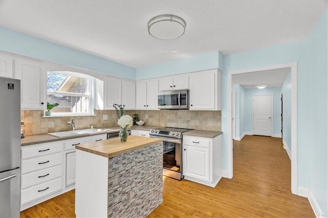 kitchen featuring a sink, butcher block counters, white cabinets, and stainless steel appliances