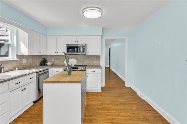kitchen featuring a sink, stainless steel appliances, wood counters, white cabinetry, and tasteful backsplash