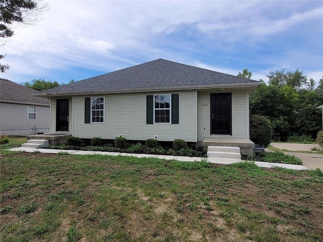 view of front facade with a front yard and a shingled roof