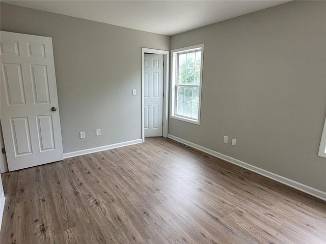 unfurnished room with visible vents, wood finished floors, and baseboards