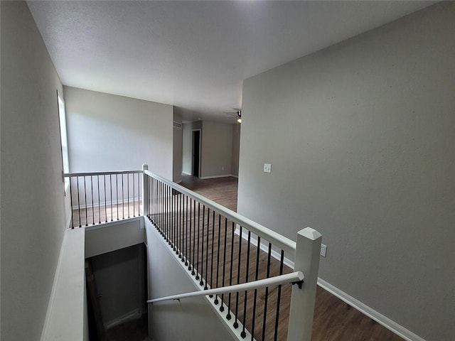 staircase featuring ceiling fan, baseboards, and wood finished floors