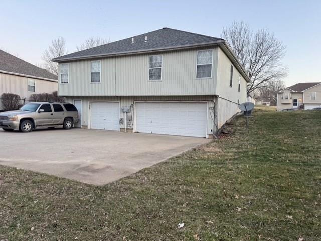 view of side of home featuring a yard, driveway, and an attached garage