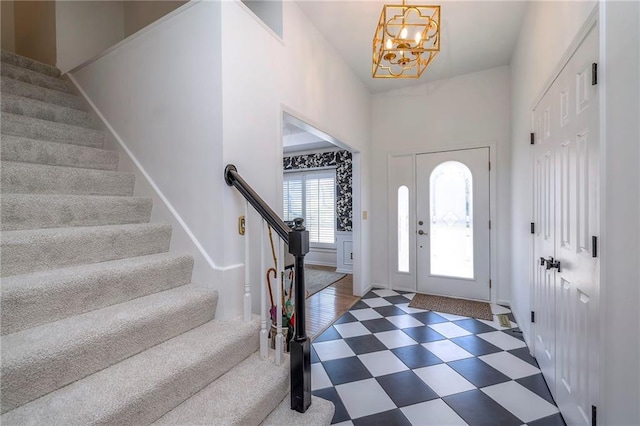 entryway featuring tile patterned floors, stairway, and an inviting chandelier