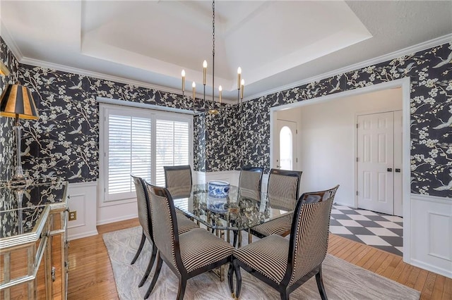 dining area with wallpapered walls, a raised ceiling, and a wainscoted wall