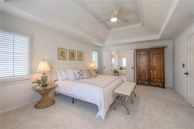 carpeted bedroom featuring visible vents, multiple windows, a raised ceiling, and connected bathroom