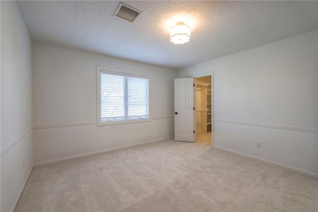 spare room featuring baseboards, carpet, visible vents, and a textured ceiling