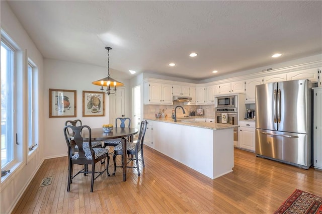 kitchen featuring white cabinetry, under cabinet range hood, light wood-style flooring, and appliances with stainless steel finishes