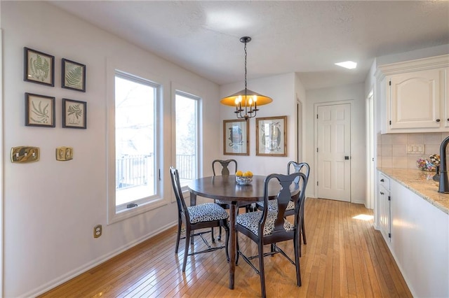 dining space with an inviting chandelier, light wood-style floors, and baseboards