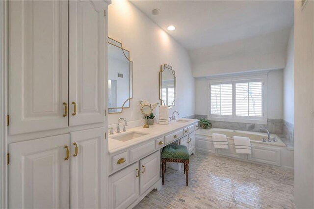 full bath with double vanity, a bath, recessed lighting, and a sink