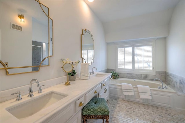 bathroom with a bath, visible vents, double vanity, and a sink