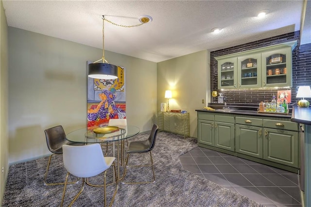 dining area featuring indoor wet bar, dark tile patterned flooring, and a textured ceiling