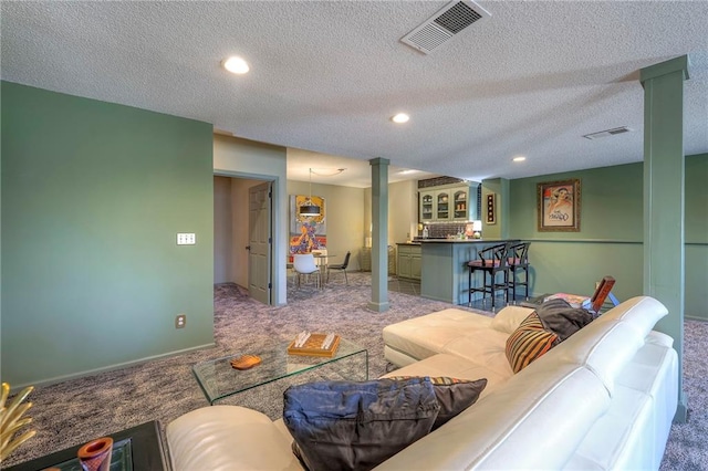 carpeted living room with recessed lighting, visible vents, a bar, and decorative columns